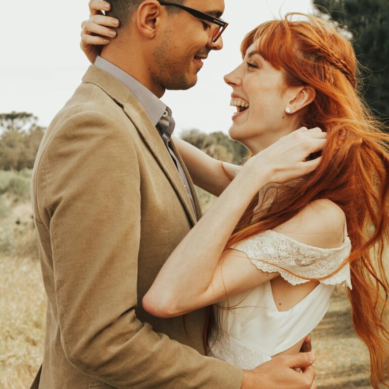 ベージュのスーツを着た男性と白いドレスを着た女性が抱き合っている
